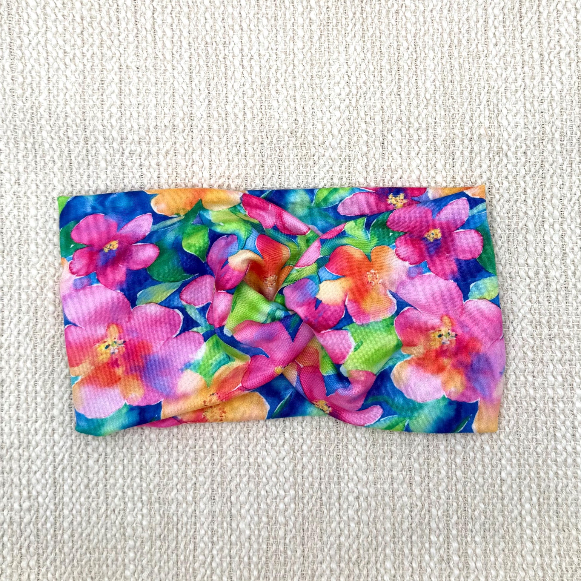 Wide, twisted headband in blue with bright, multi-color Hawaiian theme floral print.