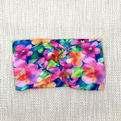 Wide, twisted headband in blue with bright, multi-color Hawaiian theme floral print.