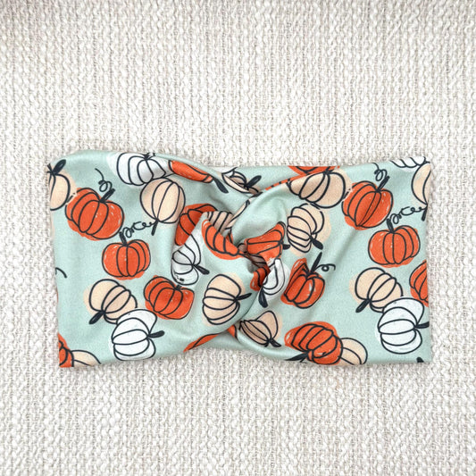 Wide, twisted, stretchy, mint green headband with pumpkin print.