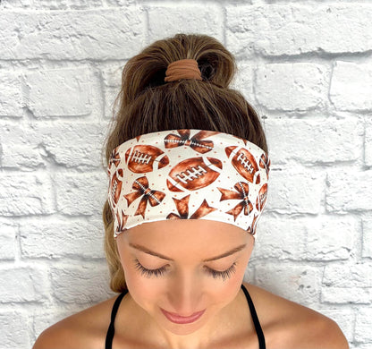 Woman with hair in ponytail wearing flat, stretchy headband in white with brown football and bow print.