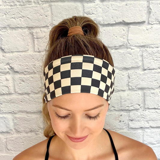 Woman with hair in ponytail wearing flat, stretchy headband in black and tan checker print.