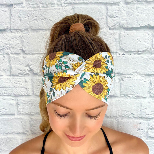 Woman with hair in ponytail wearing white, stretchy headband in white with yellow sunflower print.