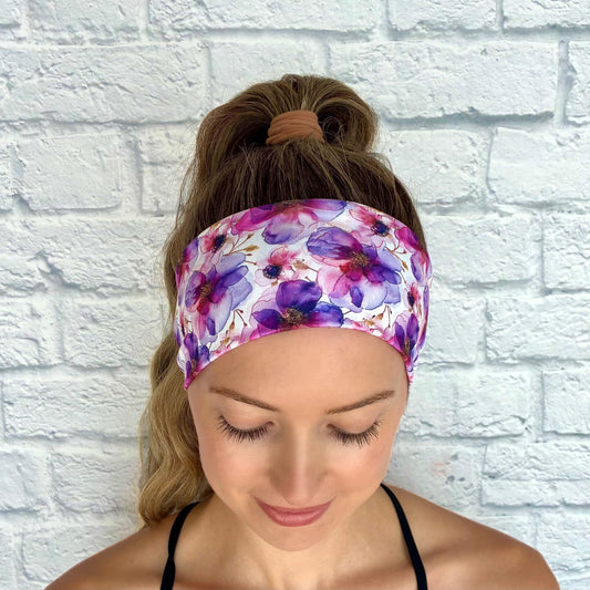 Woman with hair in ponytail wearing flat, stretchy headband with purple floral print.