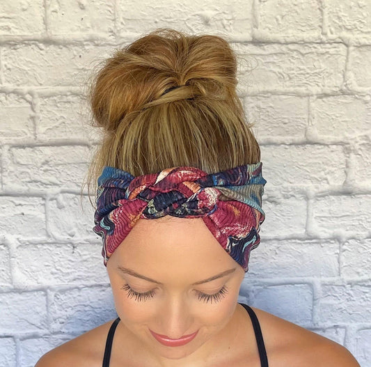 Woman with hair in bun wearing sailor knot style headband in ribbed fabric with swirl print in purple, pink, and blue colors.