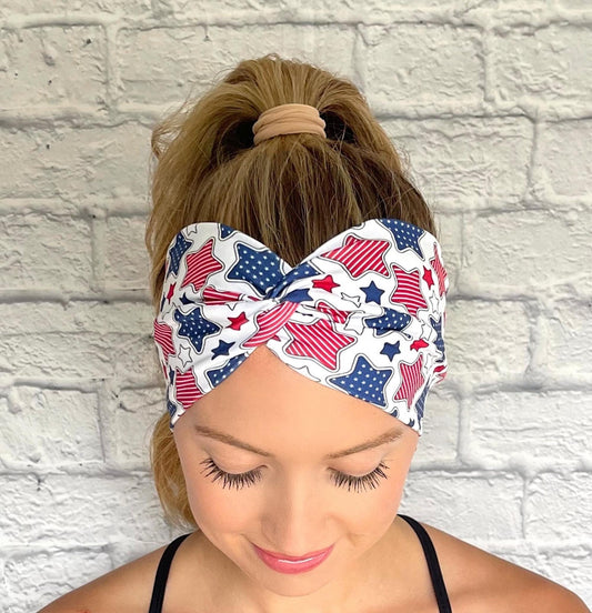 Woman with hair in ponytail wearing wide, twisted headband in white with red, white, and blue star print.