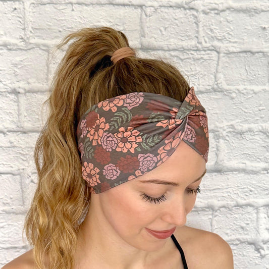 Woman with hair in ponytail wearing wide, twisted headband in gray/brown with peach color floral print.