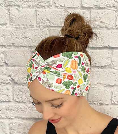 Woman with hair in bun wearing wide, twisted headband in white with vegetable theme print.