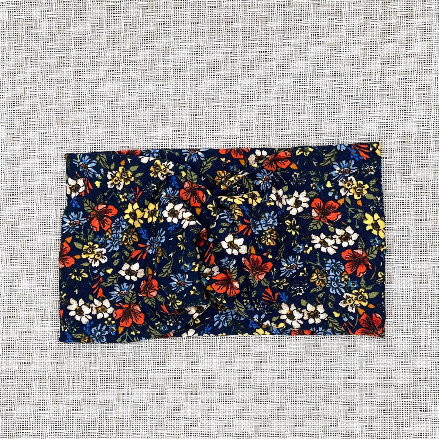 Wide, twisted headband in navy with red, white, yellow, and blue small flower print.