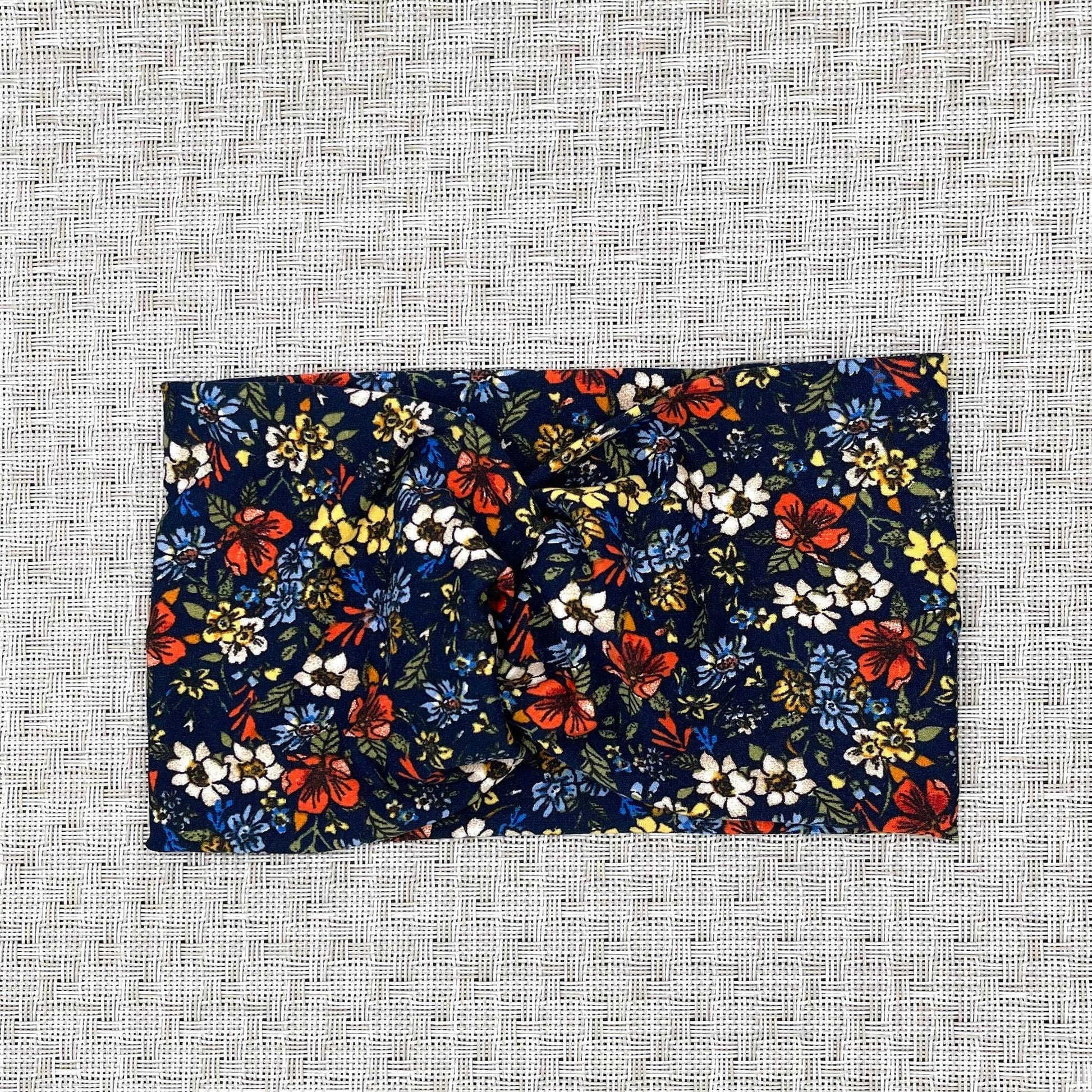 Wide, twisted headband in navy with red, white, yellow, and blue small flower print.