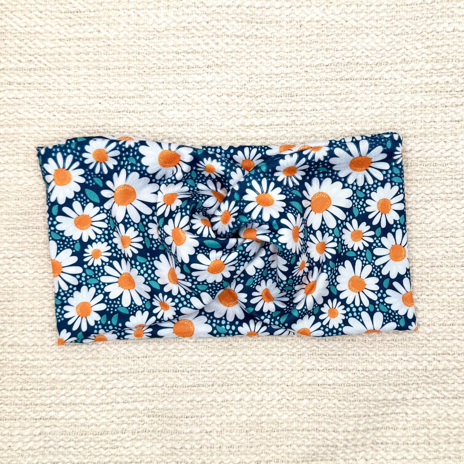 Wide, twisted headband in blue with white daisy print.