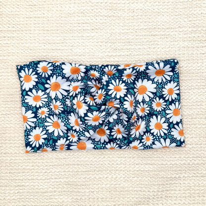 Wide, twisted headband in blue with white daisy print.