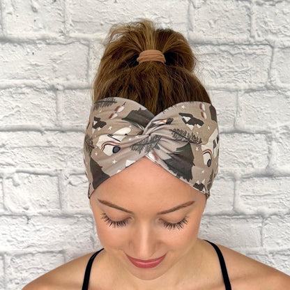 Woman with hair in ponytail wearing wide, twisted headband in tan with camping theme print.