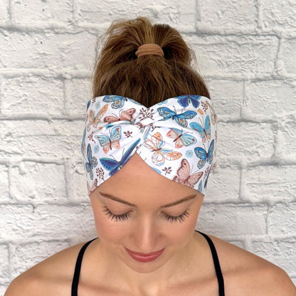Woman with hair in ponytail wearing wide, twisted headband in white with butterfly print.