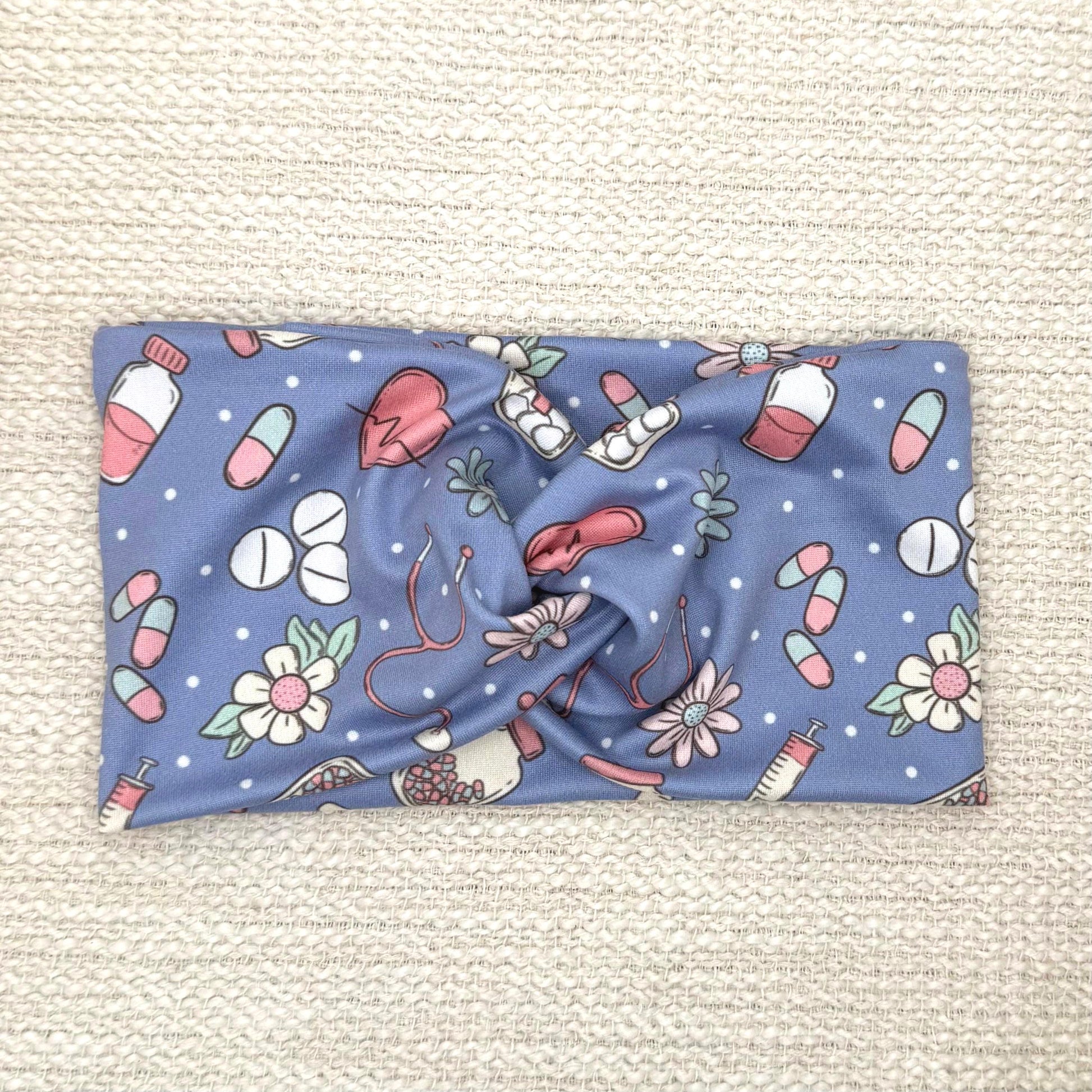 Wide, twisted headband in blue with pink, white, and mint color medical theme print.