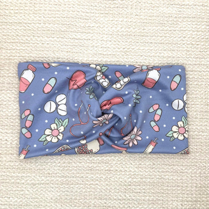 Wide, twisted headband in blue with pink, white, and mint color medical theme print.