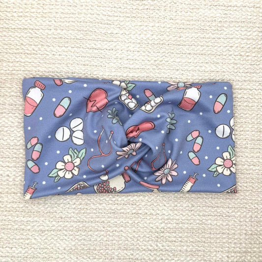 Wide, twisted headband in blue with pink, white, and mint color medical theme print.