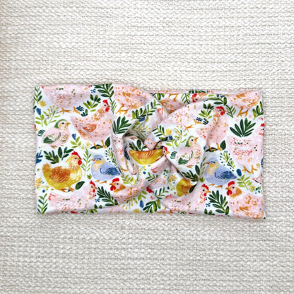 Wide, twisted headband with colorful chicken and floral print.