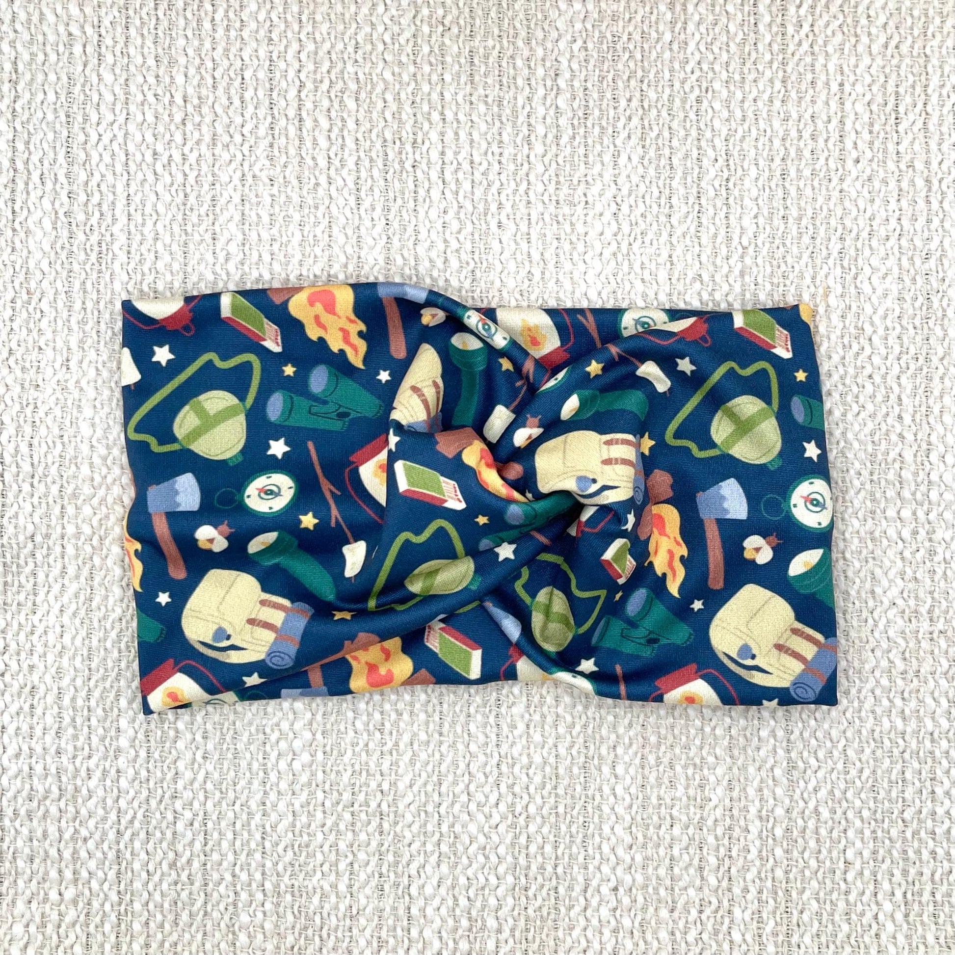 Wide navy blue camping theme headband displayed on a cream color background.