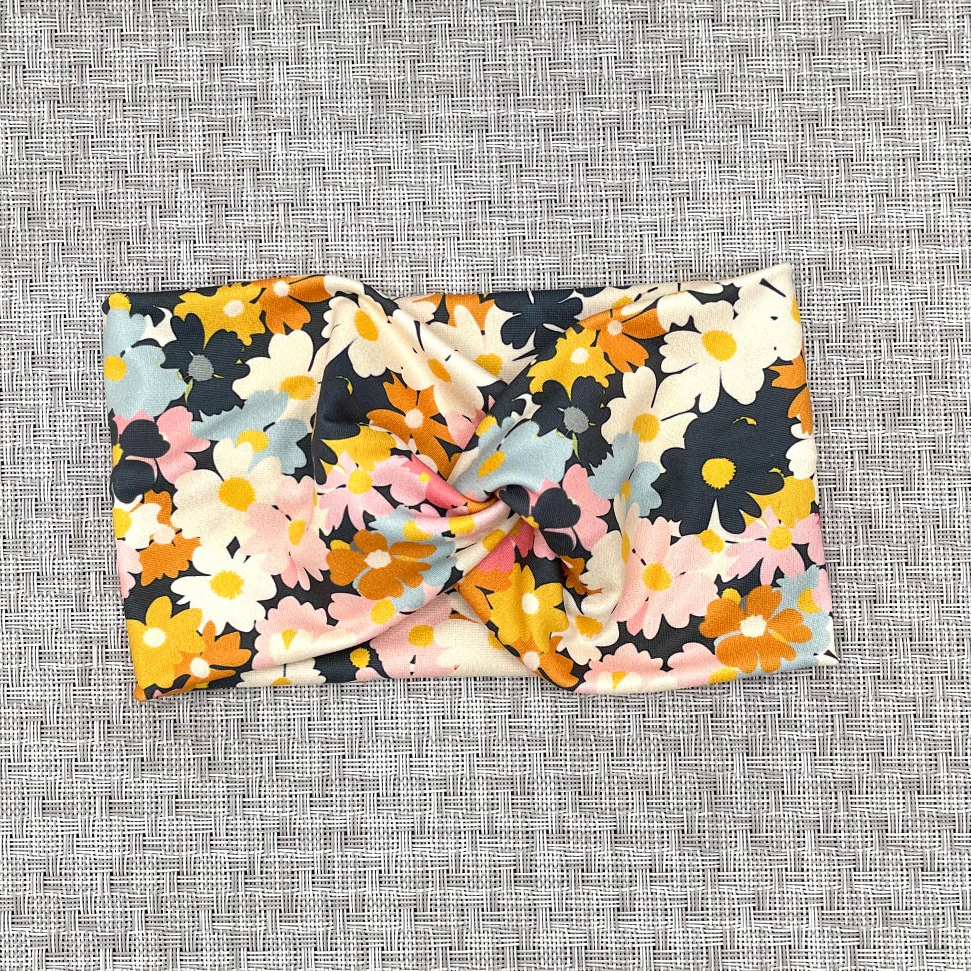 Wide, twisted headband with light and dark pink, navy, light blue, white, yellow, and orange flower print.