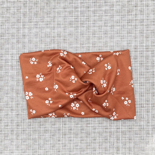 dark orange wide twist headband with small white flowers