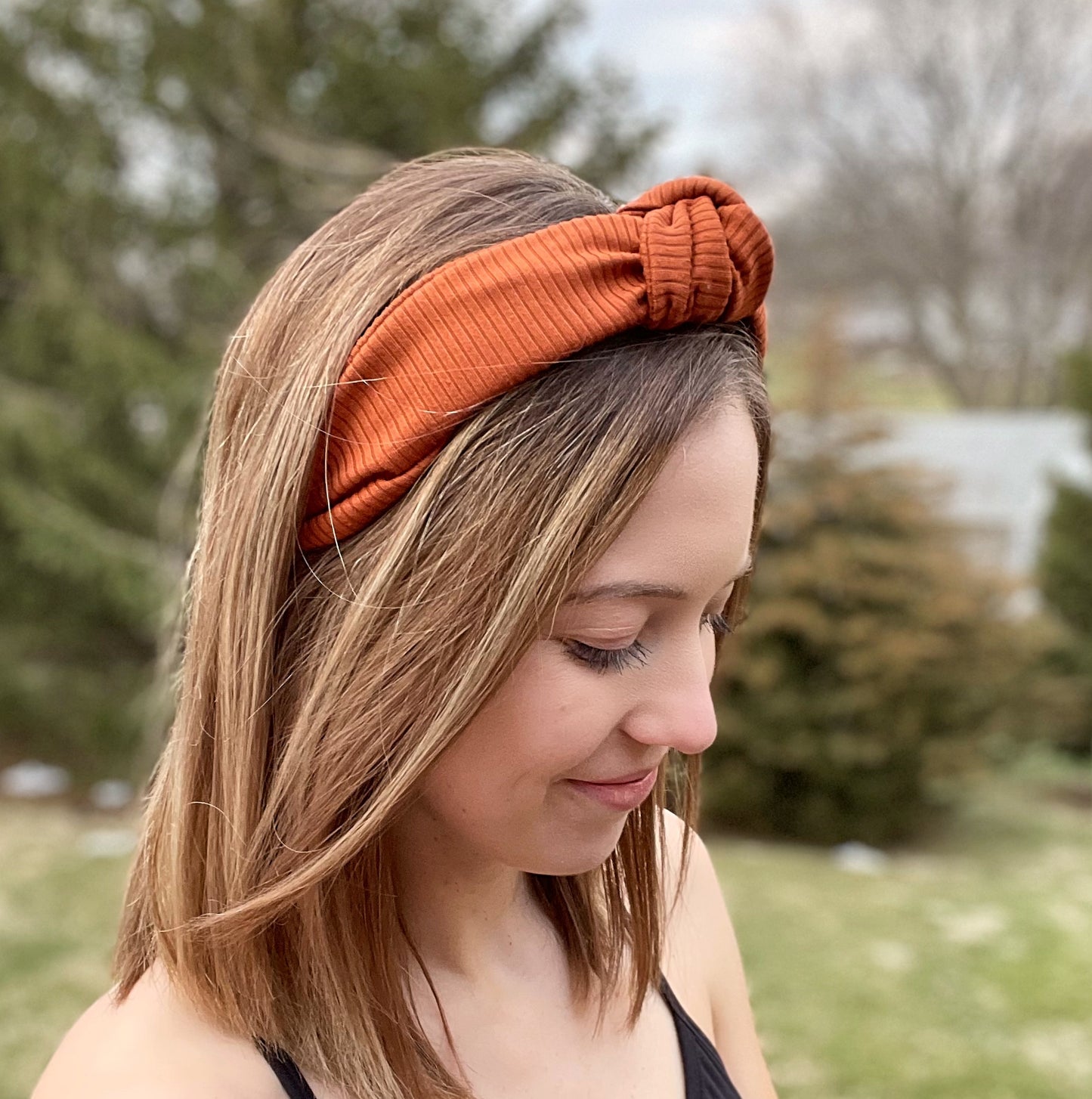 Woman wearing top knot, hard headband in burnt orange color.