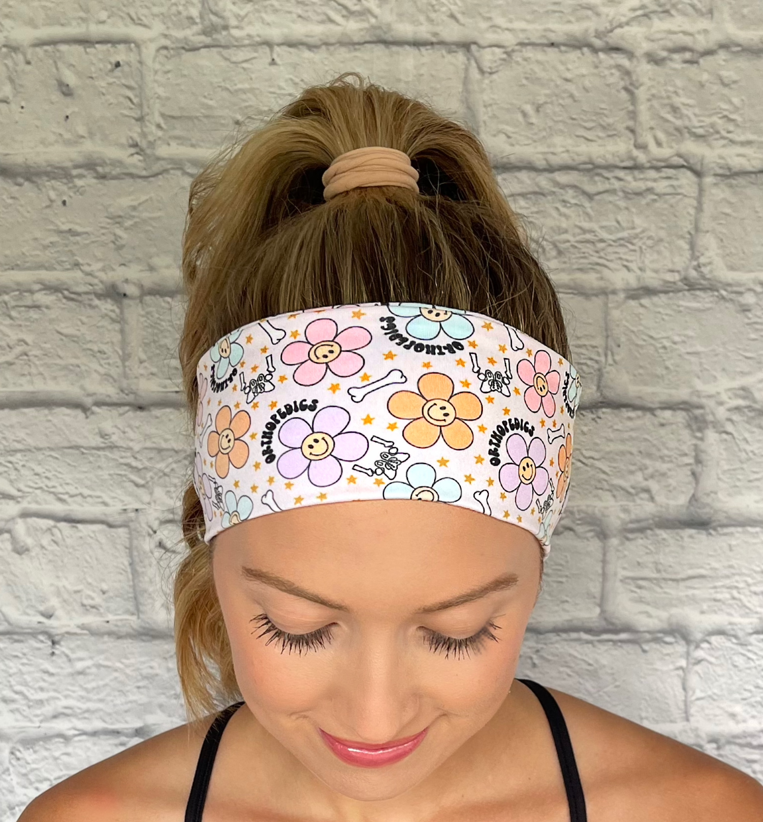 cream headband with "orthopedics" print, flowers with smiley faces, stars, and bones