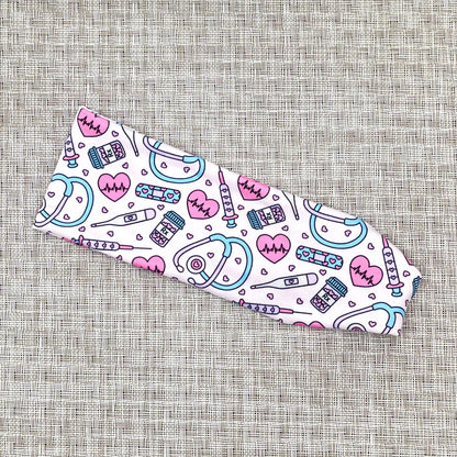 Flat, stretchy headband in light pink with pink, purple, and blue medical theme print.