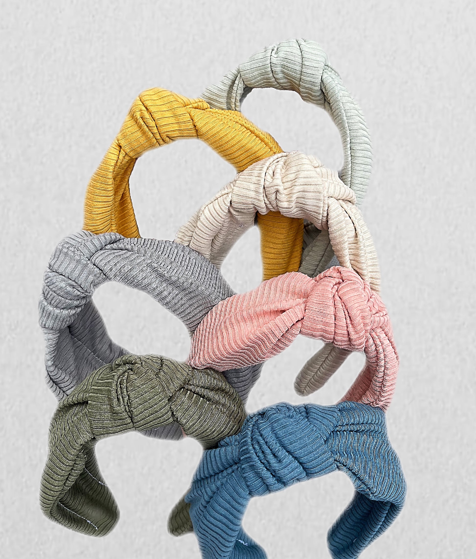 Top knot, hard headbands in varying colors- mustard yellow, light pink, olive green, light green, gray, and blue.