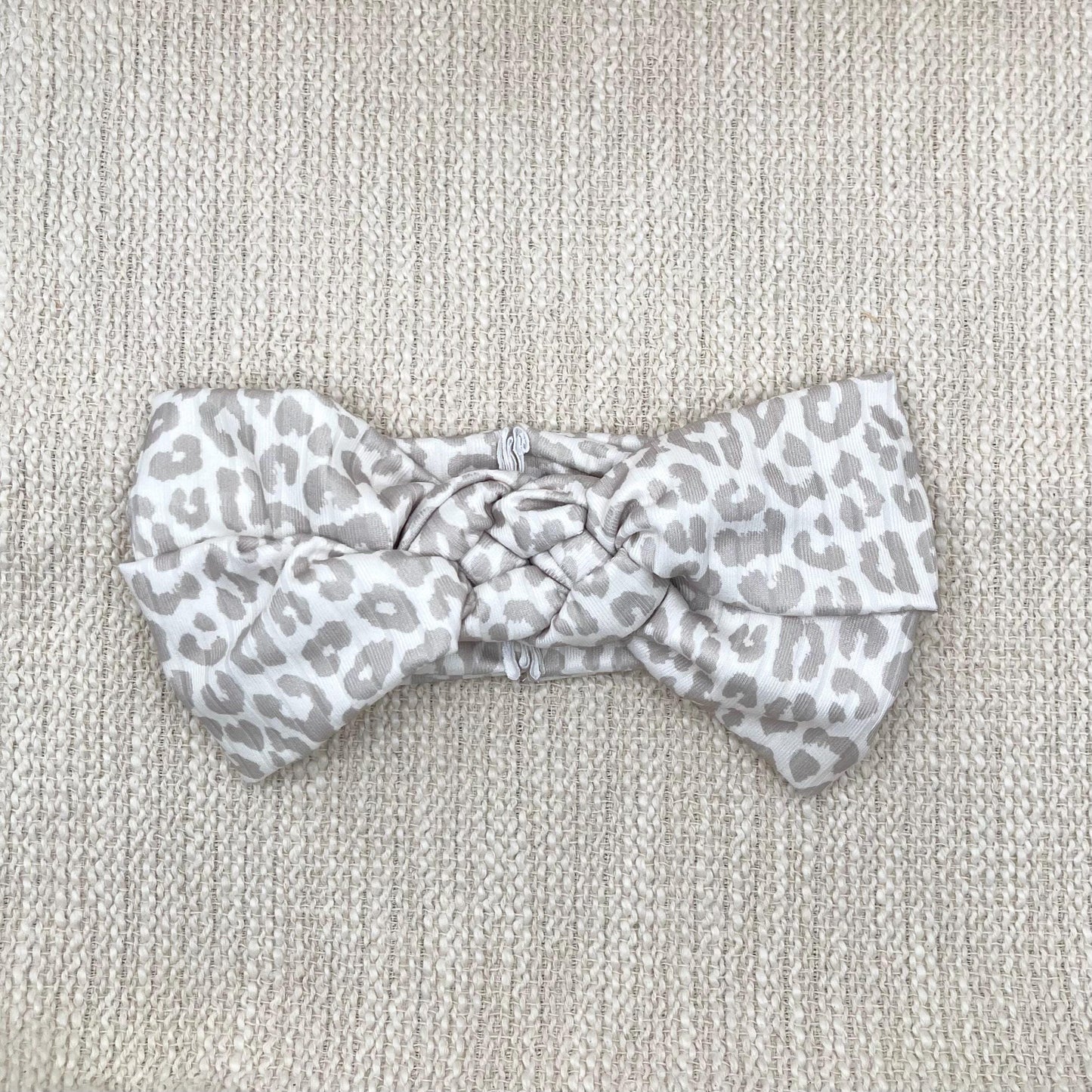 Tan and white cheetah print headband in sailor knot style with ribbed fabric.