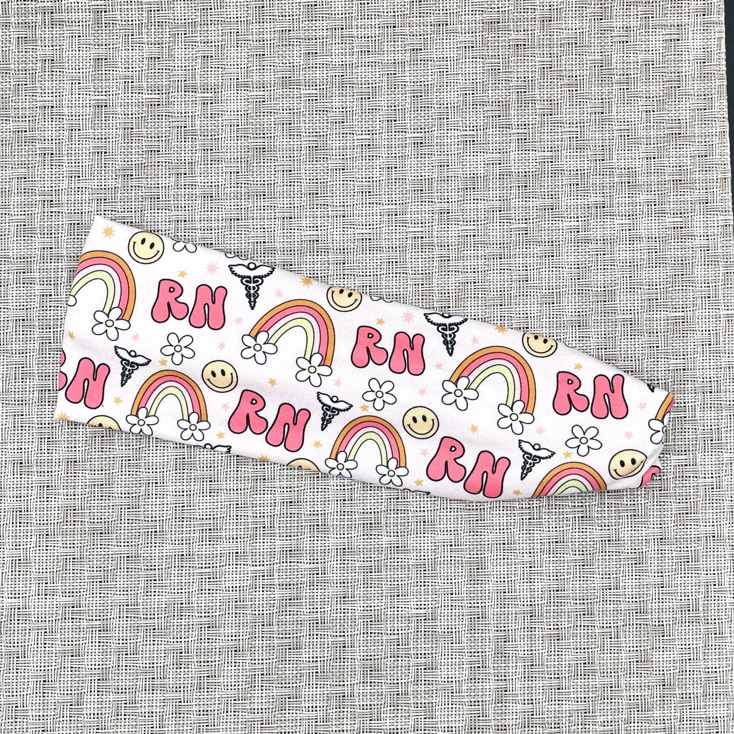 pink headband with "RN", rainbows, flowers, and smiley faces