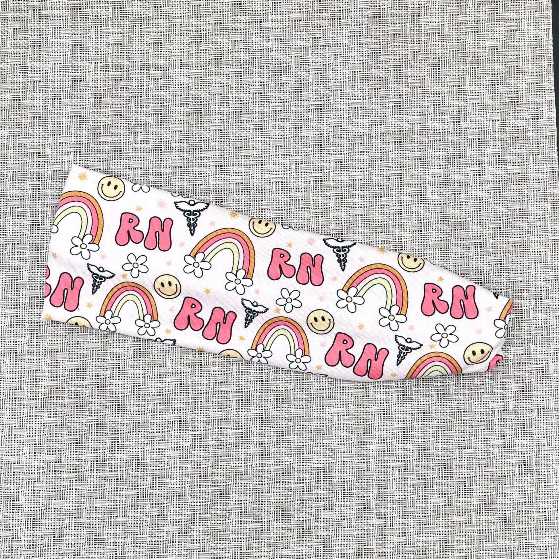 pink headband with "RN", rainbows, flowers, and smiley faces