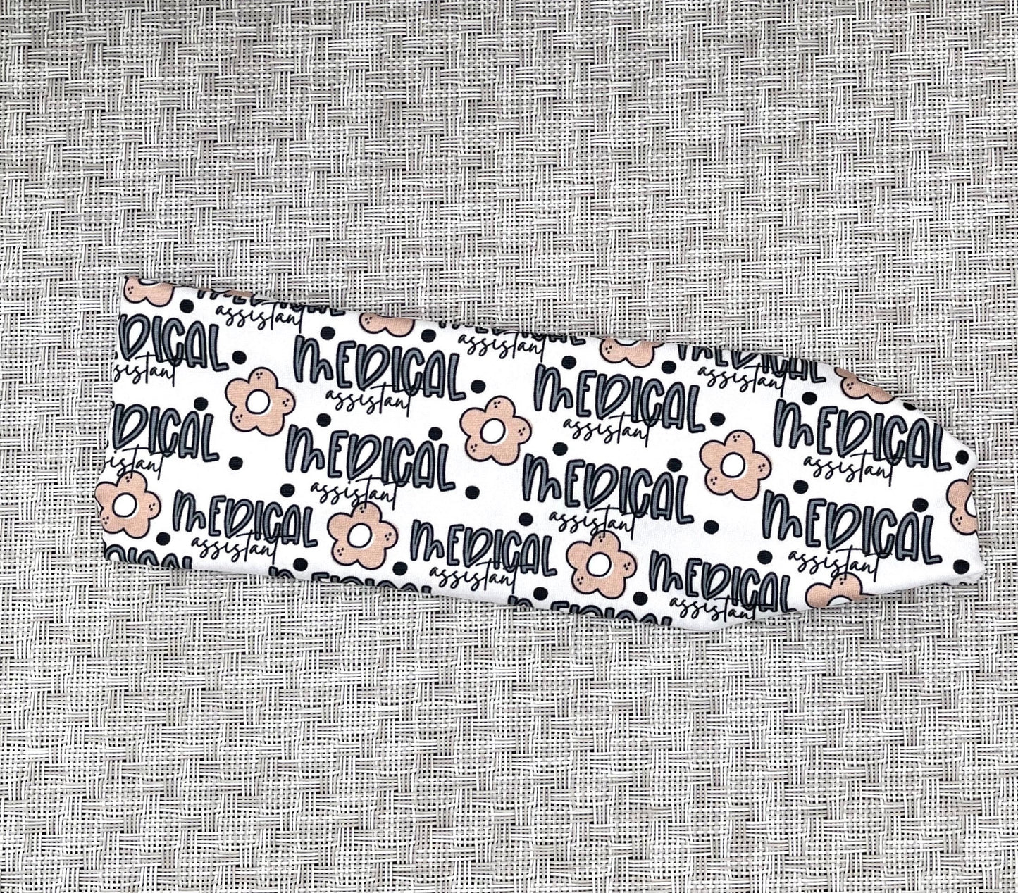 white headband with "medical assistant", flowers, and polka dot print in blue and tan