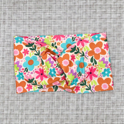 pink headband with bright pink, blue, and orange flowers