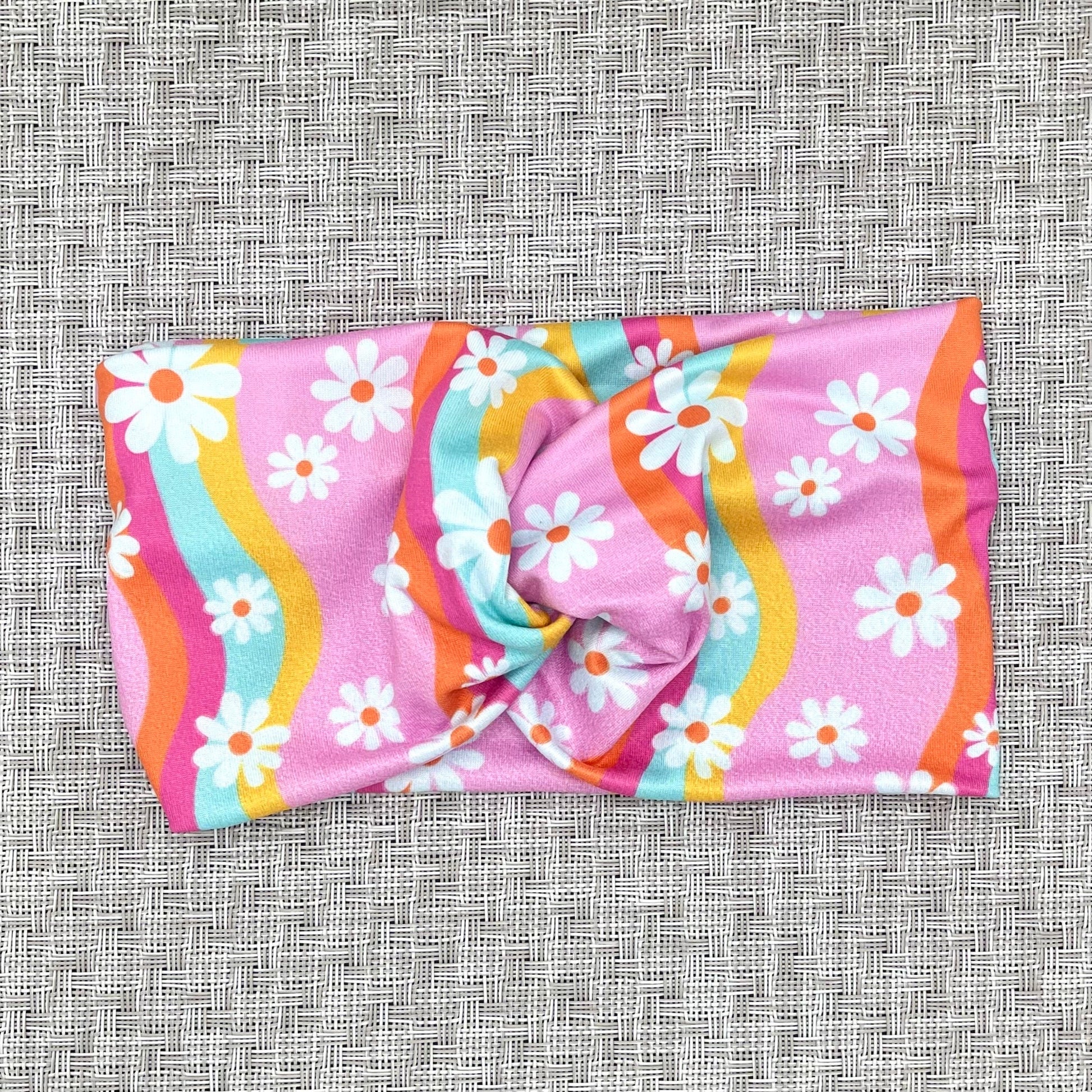 pink headband with yellow, blue, orange, and pink swirls with white flowers